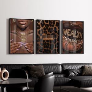 May include: Three framed art prints. The left print features a person's face with gold jewelry and the text "Black Lives Matter". The center print has a leopard print design with the text "Made of Melanin". The right print has the word "WEALTH".
