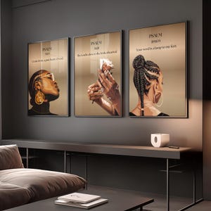 May include: Three framed art prints with black frames. Each print features a portrait of a Black woman with gold jewellery. The prints have text from Psalms. The background is a neutral beige colour. The prints are displayed above a dark grey console.
