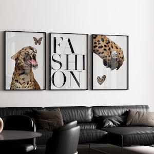 Op de afbeelding: Drie ingelijste kunstprints met een modethema. Eén print toont een brullende luipaard met een vlinder, een andere toont het woord "FASHION", en de derde toont een luipaardpoot met een diamanten ring en een hart.