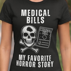 Puede incluir: Camiseta negra con el texto "MEDICAL BILLS" sobre una calavera y huesos cruzados. Debajo está el texto "MY FAVORITE HORROR STORY". Un gráfico de factura médica está a la derecha de la calavera.