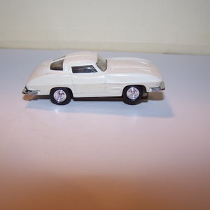 May include: White die-cast model car of a classic Corvette.