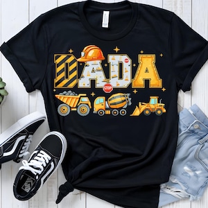 Puede incluir: Camiseta negra con la palabra "DADA" en amarillo y negro, con un casco de construcción. Debajo, ilustraciones de vehículos de construcción. Diseño temático de construcción.