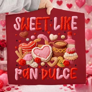 May include: A red sign with the words "SWEET LIKE PAN DULCE" in a 3D style. The sign features illustrations of baked goods, including cookies, a cupcake, and a bottle. The sign is held by a person.