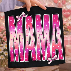 May include: Black banner with the word "MAMA" in large, pink, polka-dotted letters. The letters have a white outline and are decorated with pink bows. The background is a blurred image of flowers and the word "MOM".