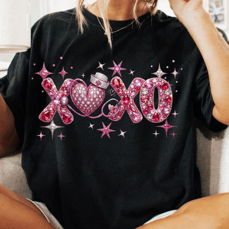 May include: Black t-shirt featuring a pink XOXO design with a heart and nurse's hat. The letters and heart are embellished with pink rhinestones and surrounded by star accents. A cute and romantic design.