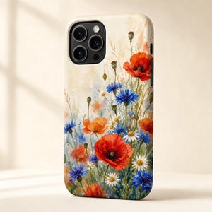 以下が含まれることがあります： 野草の野原を描いた水彩画風のスマートフォンケース。鮮やかな赤いポピー、明るい青のヤグルマギク、小さな白いデイジーが、緑の茎や蕾とともにクリーム色の背景に描かれています。