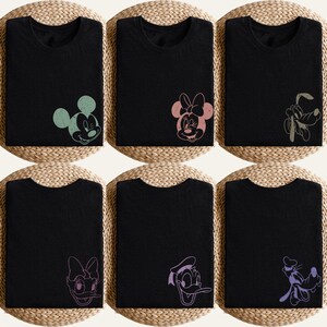 Puede incluir: Seis camisetas negras con diferentes gr&aacute;ficos de personajes de Disney. Los personajes incluyen a Mickey Mouse, Minnie Mouse, Pluto, Daisy y Donald. Los gr&aacute;ficos son en varios colores pastel, y las camisetas est&aacute;n dobladas.