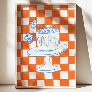 May include: A framed print featuring a whimsical cake illustration. The artwork depicts a white cake on a stand, adorned with candles, and accompanied by cupcakes. The background has an orange and white checkered pattern.