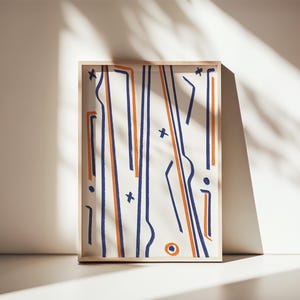 May include: A framed abstract art print featuring a white background with navy blue and orange lines and shapes. The artwork is displayed in a light-colored wooden frame, leaning against a white wall. The artwork is illuminated by natural light.