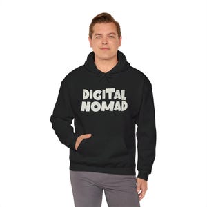 Könnte beinhalten: Schwarzer Kapuzenpullover mit dem Text "DIGITAL NOMAD" in weißen Blockbuchstaben. Der Pullover hat eine Vordertasche und eine Kapuze mit Kordelzug. Die Person trägt eine graue Hose.