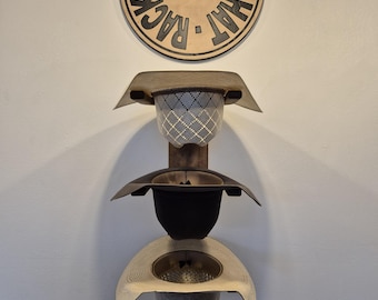 May include: A wooden hat rack with three levels, each designed to hold a hat. The rack is mounted on a white wall, with a circular sign at the top that reads "Oklahoma Hat Rack" and features an American flag.