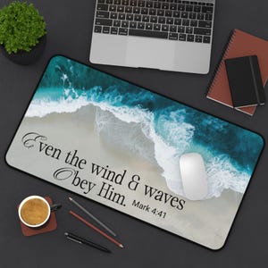 Puede incluir: Alfombrilla de ratón rectangular con una escena de playa, olas turquesas y orilla arenosa. El texto "Even the wind & waves Obey Him. Mark 4:41" está impreso. Un ratón blanco está a la derecha.