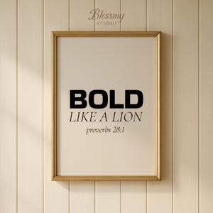 May include: A framed print with the words "BOLD LIKE A LION" in black, with "proverbs 28:1" below. The frame is gold, and the background is a light beige. The print is hanging on a light beige wooden wall.