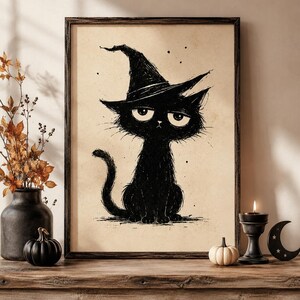 Könnte beinhalten: Ein gerahmter Kunstdruck mit einer schwarzen Tuschezeichnung einer Katze, die einen spitzen Hexenhut trägt. Die Katze hat große, ausdrucksstarke Augen und ein strukturiertes, skizzenhaftes Aussehen auf beigem Hintergrund in einem dunklen Holzrahmen.