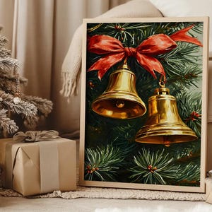 Könnte beinhalten: Ein gerahmter Kunstdruck mit einem Gemälde von zwei glänzenden goldenen Glocken, die an einem leuchtend roten Band vor einem Hintergrund aus dunkelgrünen Tannennadeln hängen. Das Bild befindet sich in einem hellen Holzrahmen mit schlichtem Rand.
