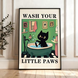 Könnte beinhalten: Ein gerahmter Kunstdruck mit einer schwarzen Katze in einer grünen Badewanne voller blauer Seifenblasen. Der Text WASH YOUR LITTLE PAWS ist oben und unten in Schwarz gedruckt. Die Badszene zeigt einen Spiegel, ein Handtuch und Flaschen.