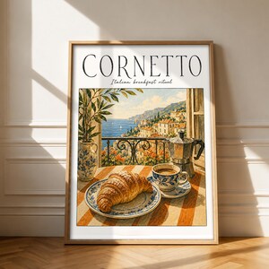 Könnte beinhalten: Ein gerahmter Kunstdruck mit dem Titel CORNETTO Italian breakfast ritual, der eine gemalte Szene mit einem Croissant auf einem Teller, einer Kaffeetasse und einem Espressokocher auf einem gestreiften Tisch vor einer Küstenlandschaft zeigt.