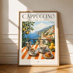 Könnte beinhalten: Ein gerahmter Kunstdruck mit dem Titel CAPPUCCINO und dem Text Made in Italy, buon appetito! Die Illustration zeigt eine italienische Küstenstadt, eine Moka-Kanne aus Metall, zwei blau-weiß gemusterte Kaffeetassen und ein Gebäck auf einem gestreiften Tisch.