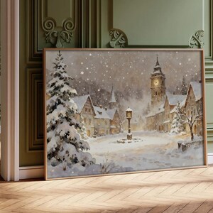 May include: A rectangular wall art print depicting a snowy village scene with a tall clock tower, a central street clock, and snow-covered pine trees. The painting features soft, muted tones of white, gray, and brown, capturing a winter atmosphere.