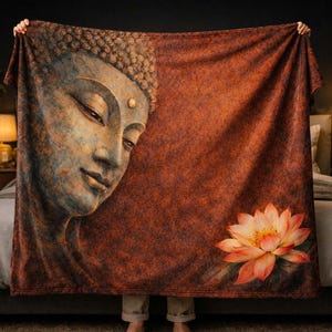 May include: A large, rectangular blanket featuring a detailed illustration of Buddha's face on the left side, transitioning to a textured reddish-brown background. A lotus flower is depicted on the lower right. The blanket is held up by a person.