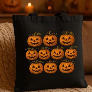May include: Black tote bag featuring a repeating pattern of orange jack-o'-lanterns with carved faces. The pumpkins have green vines and are set against a black background. The bag has two black handles.