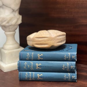 May include: A stack of three blue vintage books with gold lettering and a decorative wooden box on top. The books are titled "Ruby's Lips and Downs at School Vacation" by Estes & Lauriat.