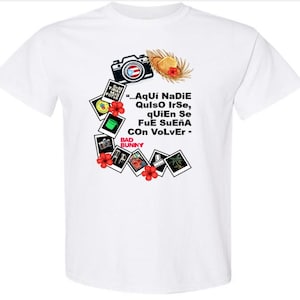 Può includere: T-shirt bianca con un design grafico con una macchina fotografica, un cappello di paglia e foto in stile polaroid. Il design include testo in spagnolo e le parole "BAD BUNNY". Fiori di ibisco rossi accentuano il design.