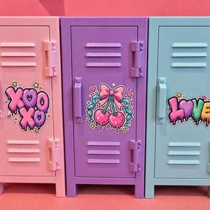May include: Three miniature metal lockers in pastel pink, purple, and light blue. Each locker features horizontal vents, a vertical handle, and a colorful sticker. The pink locker displays XOXO, the purple has cherries with a bow, and the blue says LOVE.