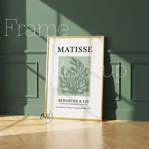 May include: A framed art print featuring a Matisse design with the text "MATISSE" and "BERGRUEN & CIE". The print has a gold frame and is displayed against a green wall and wooden floor. The text "Frame Mockup" is also visible.