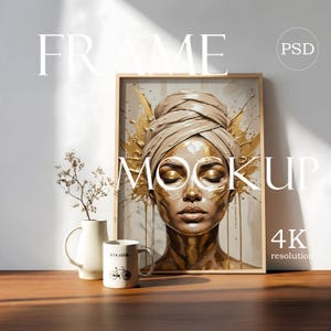 May include: A rectangular wooden frame containing an art print of a person with a head wrap and gold paint on their face. Next to the frame is a white ceramic vase with dried branches and a white mug with the text BONJOUR and a bicycle graphic.