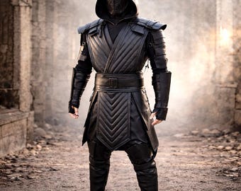 Puede incluir: Un disfraz negro con capucha, máscara facial, hombreras y una túnica acolchada de cuero. El disfraz incluye un cinturón ancho, protectores de brazos y pantalones y botas a juego. El atuendo está diseñado para cosplay o eventos de disfraces.