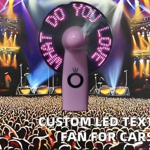 Peut inclure: Un ventilateur LED rose affichant les mots "BE YOU HAVE LOVE" en lumières roses. Le ventilateur a un anneau noir autour des lumières et un cercle noir avec un logo de couronne. Le texte "CUSTOM LED TEXT FAN FOR CARS" est en bas.