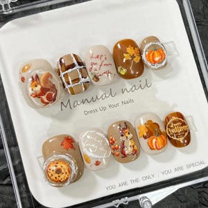 May include: A set of false nails with autumnal designs. The nails display images of squirrels, pumpkins, leaves, and donuts. The text "Manual nail" and "Dress Up Your Nails" are printed on the card. The text "YOU ARE THE ONLY - YOU ARE SPECIAL" is also printed on the card.