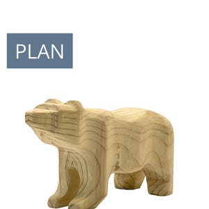 May include: A wooden bear figurine, carved from light-coloured wood, stands on all fours. The bear has a blocky, geometric design with visible wood grain. A blue rectangle with the word "PLAN" in white text is in the upper left corner.