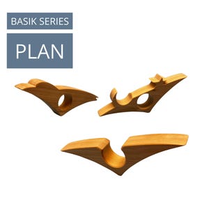 May include: Three wooden wine glass holders in a light brown color. Each holder has a unique design with curved edges and circular openings. The text "BASIK SERIES" and "PLAN" are in a blue rectangle in the upper left corner.