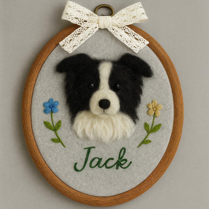 May include: An oval-shaped, framed felt art piece featuring a black and white dog portrait. The dog's name, "Jack," is embroidered in green script. The piece is adorned with embroidered flowers and a lace bow.