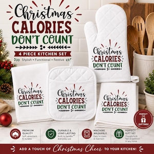 Op de afbeelding: Een vierdelige witte keukenset bestaande uit een ovenwant, een vierkante pannenlap en twee theedoeken. Elk item is voorzien van de zwarte, rode en groene tekst "Christmas CALORIES DON'T COUNT" met decoratieve krullen en een gewatteerde textuur.