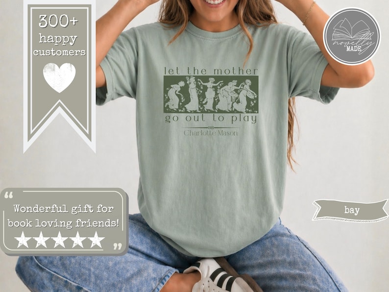 May include: A sage green short-sleeve t-shirt featuring a dark green rectangular graphic with a line of dancing figures. The text reads let the mother go out to play and Charlotte Mason. The shirt is paired with blue denim jeans and white trainers.