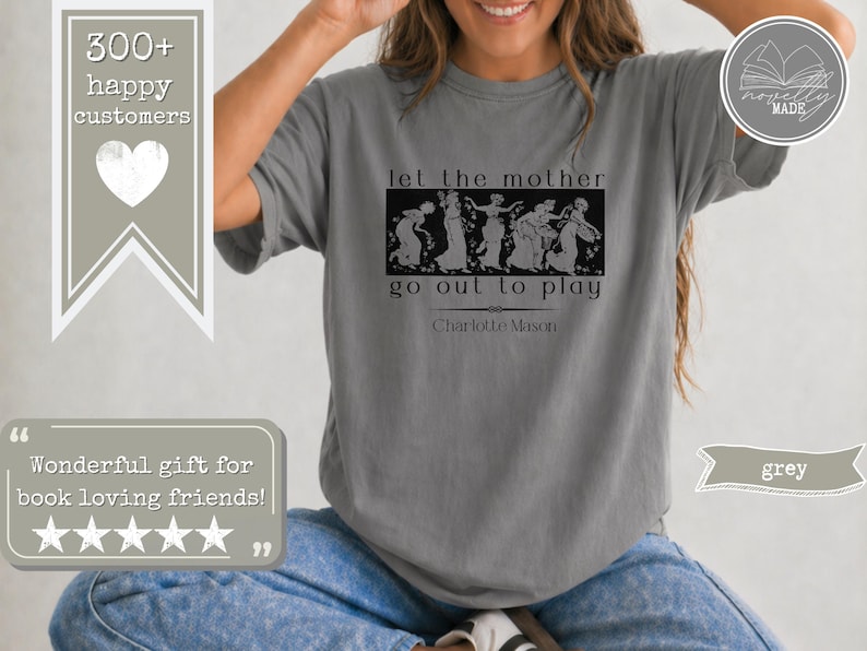 May include: A grey short-sleeved t-shirt featuring a black graphic print of classical figures in a rectangular frame. The text reads let the mother go out to play and Charlotte Mason. The shirt has a crew neckline and a relaxed, loose fit.