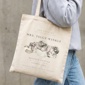 May include: A beige canvas tote bag featuring a printed illustration of three hedgehogs from The Tale of Mrs. Tiggy-Winkle by Beatrix Potter. The text reads The Tale of Mrs. Tiggy-Winkle, Beatrix Potter, London 1905, and Her eyes went twinkle, twinkle.