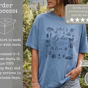Pu&ograve; includere: Una t-shirt color blu jeans con una stampa grafica blu scuro di vari insetti, piante e il testo: My dear you have come here to learn to live. Charlotte Mason. La maglietta presenta un girocollo e maniche corte, mostrando un design ispirato alla natura.