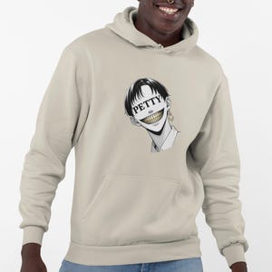 Surreal manga-style hoodie with bold "petty" face, sharp teeth, & winged mic earring. Streetwear with unapologetic bite.