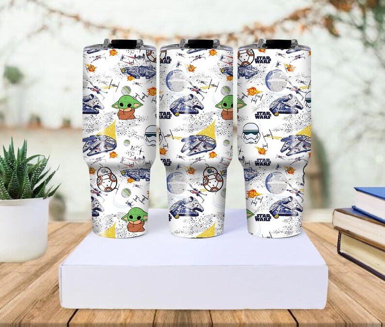 Op de afbeelding: Drie witte ge&iuml;soleerde bekers met een Star Wars-thema. Het ontwerp bevat illustraties van de Millennium Falcon, Baby Yoda, Stormtroopers en andere personages en elementen uit de Star Wars-franchise.