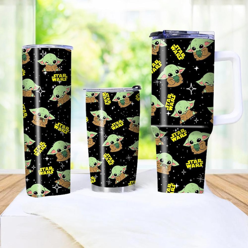 May include: Three insulated tumblers featuring a black background and a repeating pattern of a green alien character from Star Wars. The tumblers have the words "STAR WARS" in yellow.
