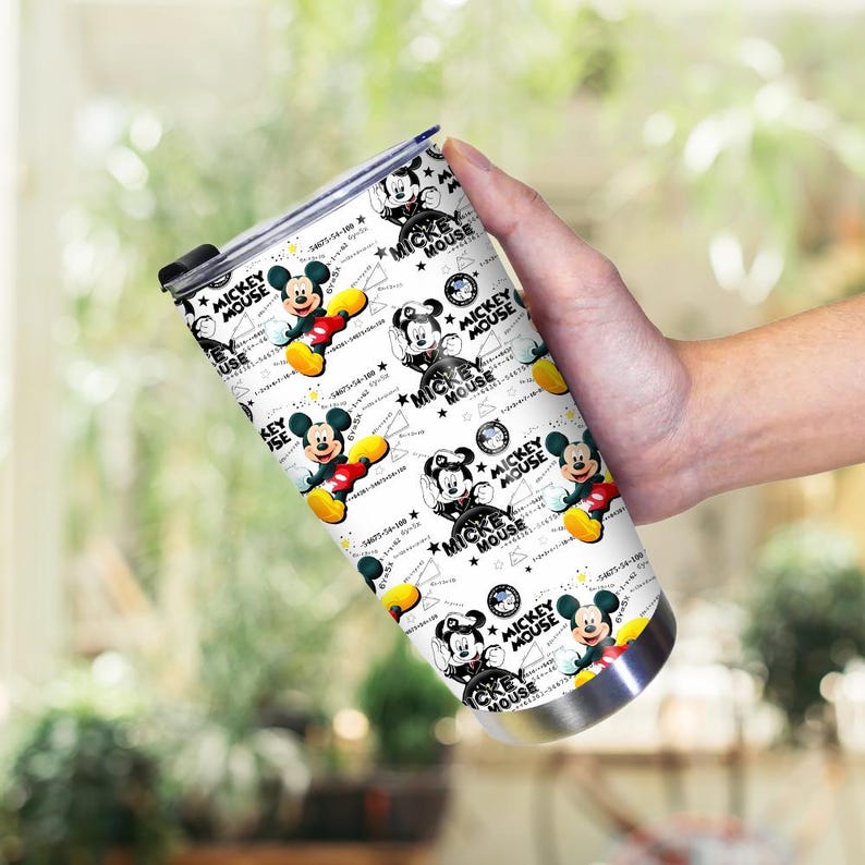 May include: A stainless steel tumbler featuring a repeating pattern of Mickey Mouse illustrations in red, yellow, black, and white. The tumbler has a black lid and is held against a blurred green background.