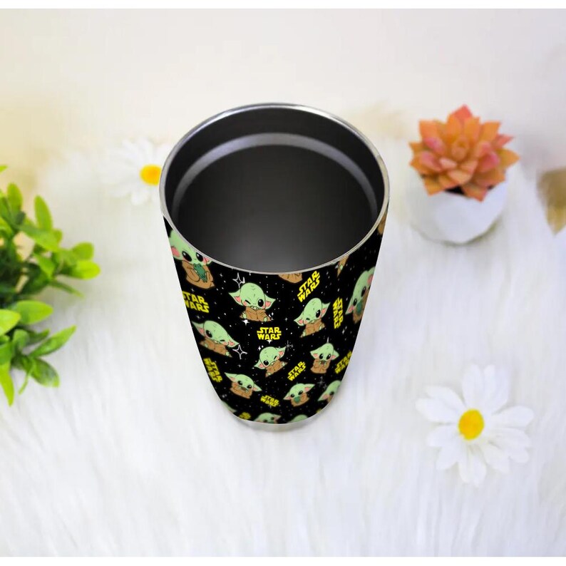 May include: A stainless steel tumbler with a repeating pattern of Grogu from Star Wars. The design features Grogu in different poses, with the Star Wars logo in yellow on a black background.