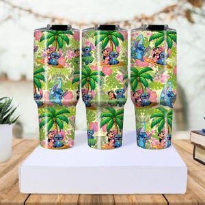 May include: Three insulated tumblers with a tropical design featuring palm trees, pink flowers, and cartoon characters. The tumblers are decorated with a repeating pattern of the characters surfing and enjoying the beach. The tumblers are approximately 10 inches tall.