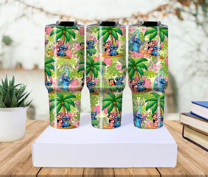 May include: Three insulated tumblers with a tropical design featuring palm trees, pink flowers, and cartoon characters. The tumblers are decorated with a repeating pattern of the characters surfing and enjoying the beach. The tumblers are approximately 10 inches tall.