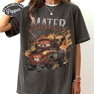 May include: Dark grey Comfort Colors t-shirt with a graphic of Mater from the film Cars. The image shows Mater with the word "MATER" above him, with lightning bolts and a distressed design.