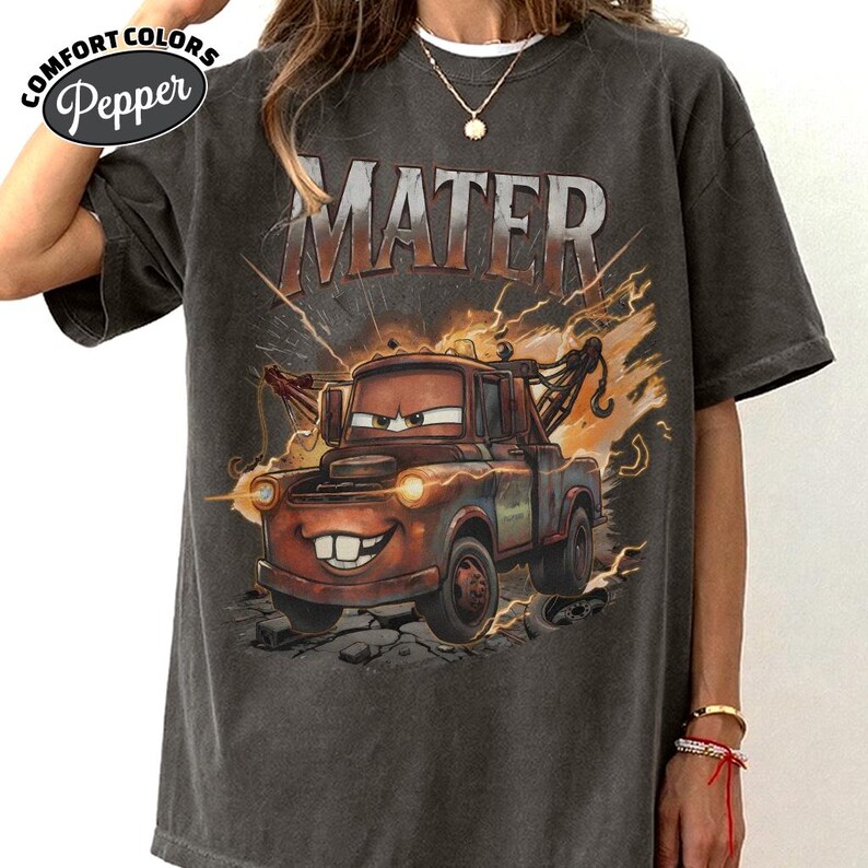 May include: Dark grey Comfort Colors t-shirt with a graphic of Mater from the film Cars. The image shows Mater with the word "MATER" above him, with lightning bolts and a distressed design.